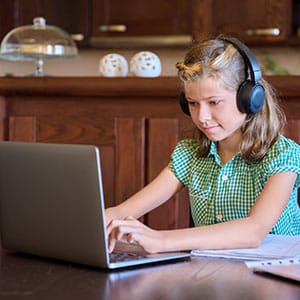 young girl using computer with headphones on